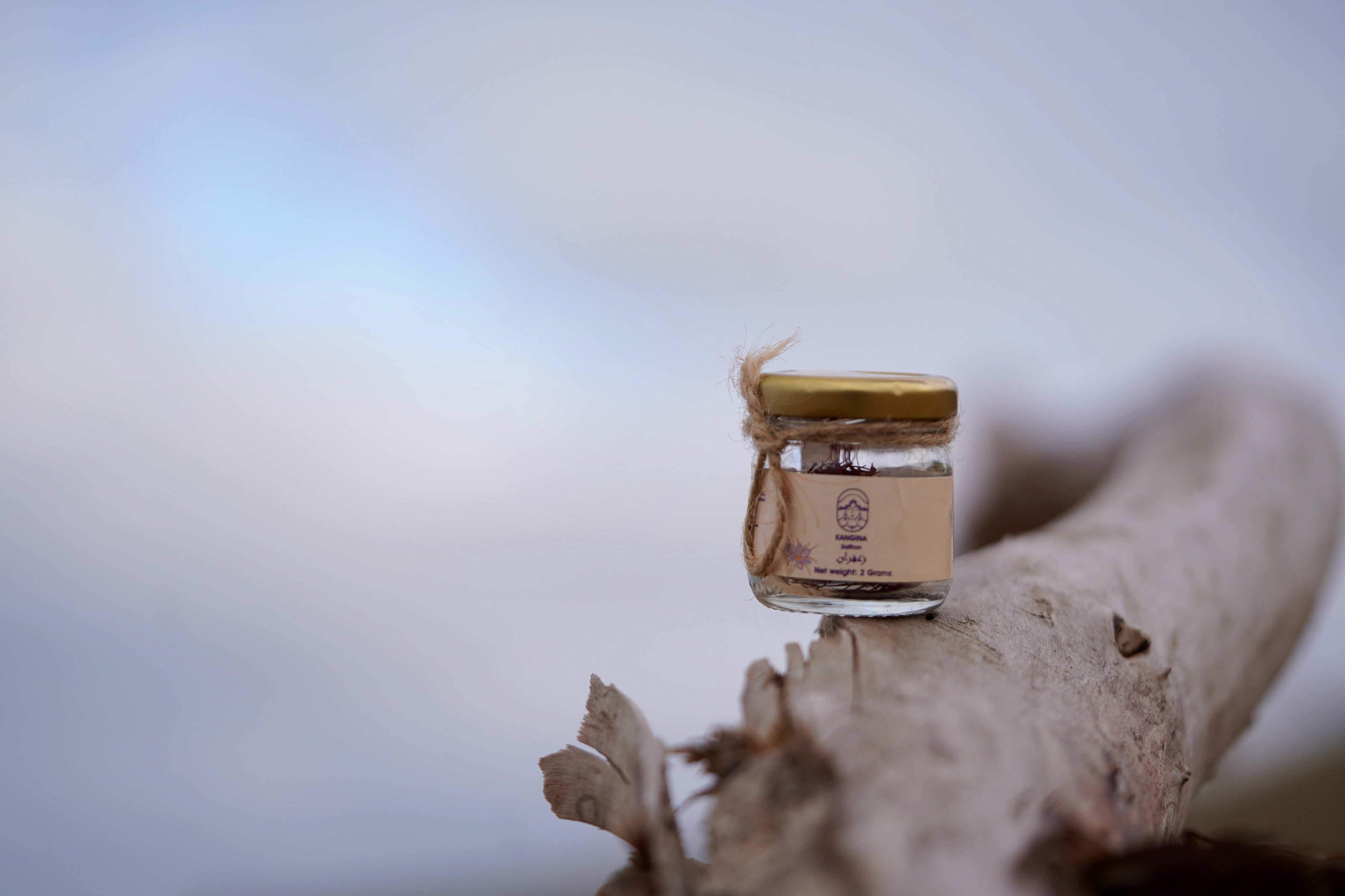 A jar of Kangina Afghan saffron resting on driftwood